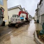 Backhoe in a alley amongst townhouses on a rainy day