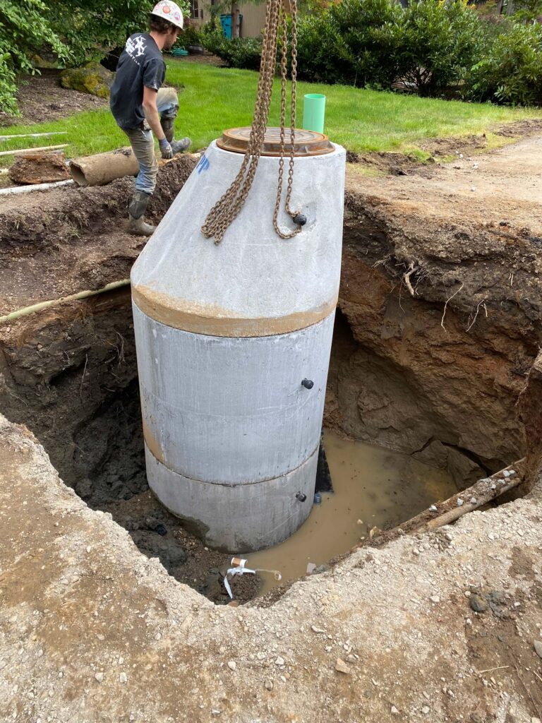 Construction worker at a residential home installing a new sewer being lowered into a large hole