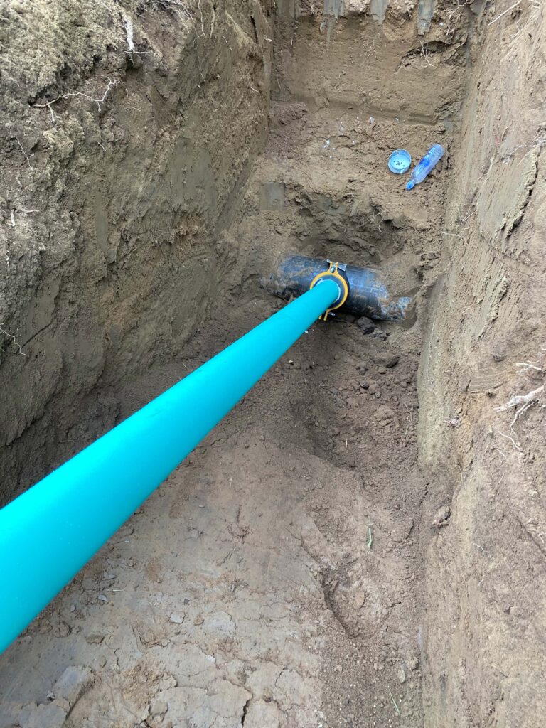 Deep excavation hole with green sewer line